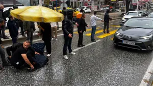 Otomobilin çarptığı kadına esnaftan şemsiyeli yardım