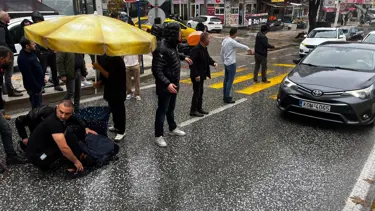 Otomobilin çarptığı kadına esnaftan şemsiyeli yardım