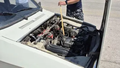 Arabanın motoruna giren yılanı sopayla çıkardı