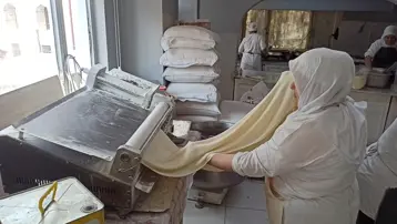 İnce ince açılan yufkanın arasına ceviz serpiliyor. Meşhur beyaz rengi böyle ortaya çıkıyor