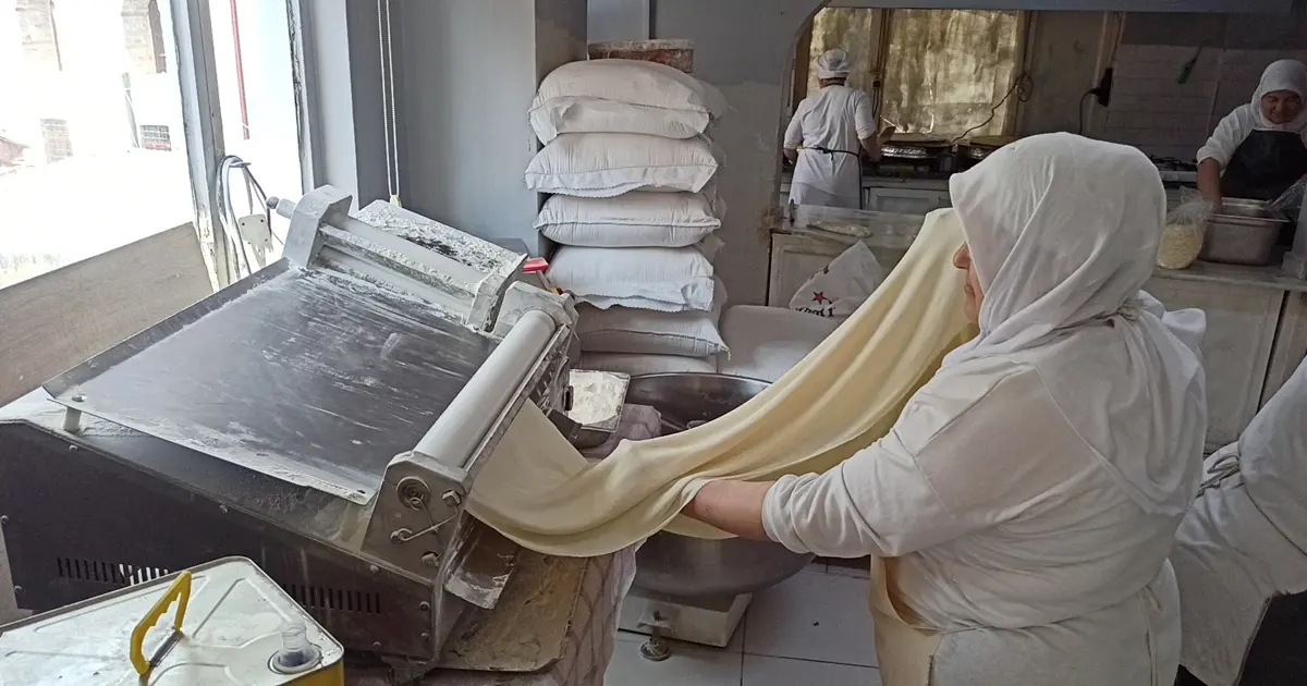 İnce ince açılan yufkanın arasına ceviz serpiliyor. Meşhur beyaz rengi böyle ortaya çıkıyor