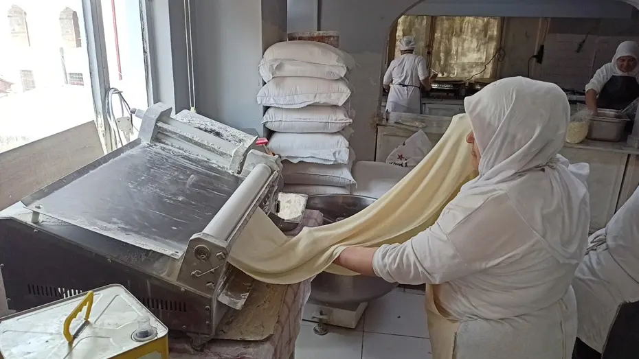 İnce ince açılan yufkanın arasına ceviz serpiliyor. Meşhur beyaz rengi böyle ortaya çıkıyor