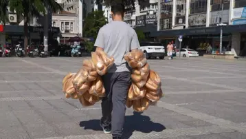 Elinde 100 ekmek var. Her gün onlarca poşeti tek seferde taşıyor