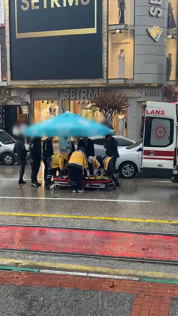 Otomobilin çarptığı yayayı yağmurdan korumak için çevredekiler şemsiye tuttu