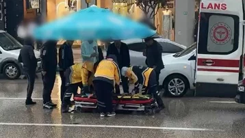 Otomobilin çarptığı yayayı yağmurdan korumak için çevredekiler şemsiye tuttu