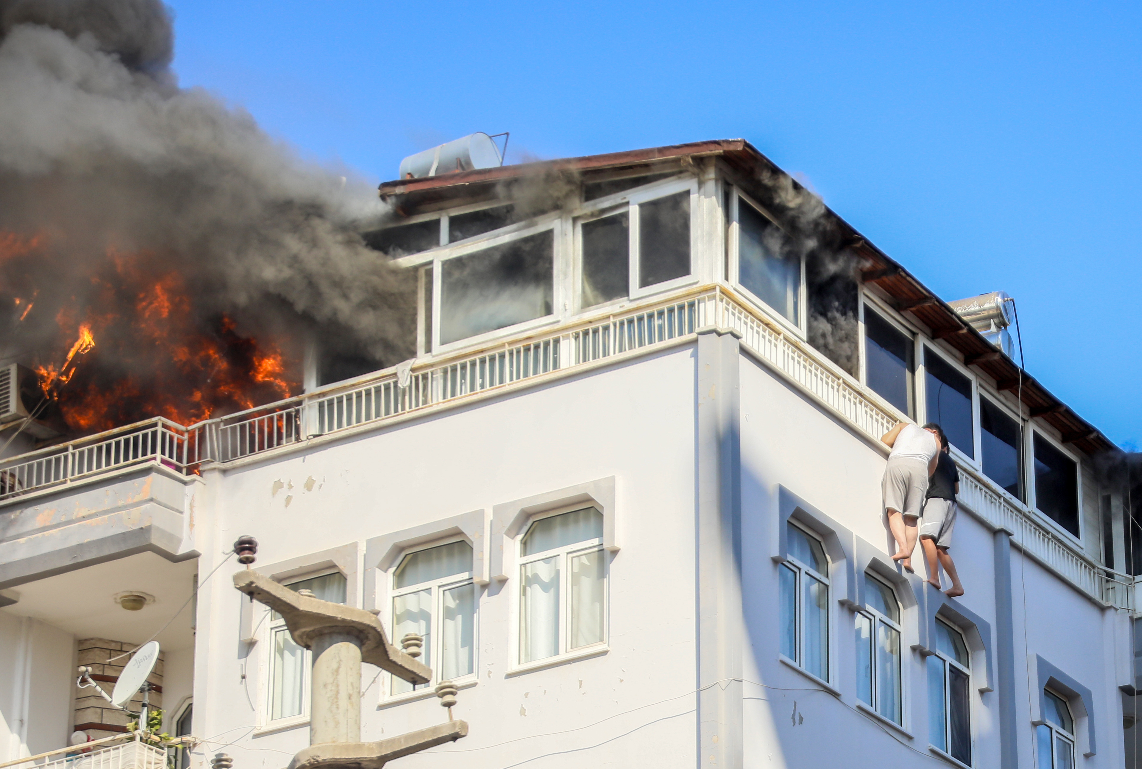 Alevler arasında ölmemek için pencereden sarkarak beklediler. İtfaiye son anda kurtardı